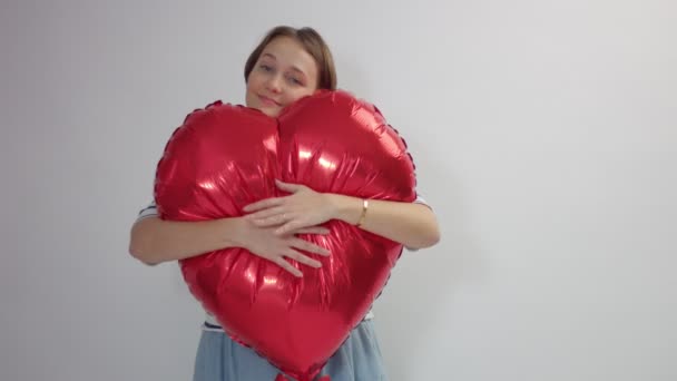 Mujer caucásica abraza un enorme corazón rojo y mantenerlo — Vídeos de Stock