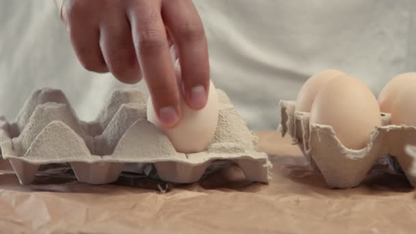 Мужчина берет яйца из корзины и кладет их в баксы — стоковое видео