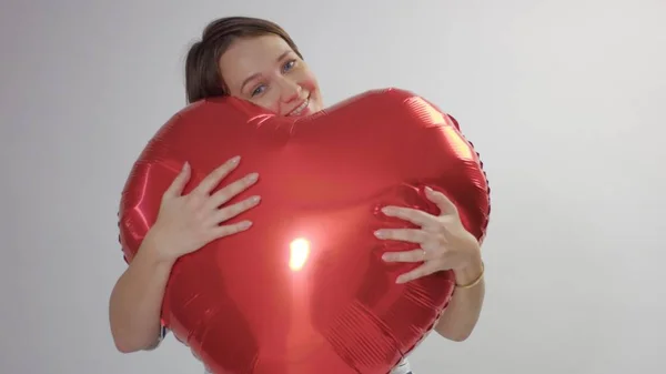 Mujer caucásica abraza un enorme corazón rojo y mantenerlo — Foto de Stock