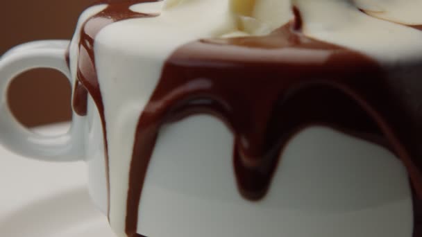 Xícara de chocolate quente com um creme e chocolate branco líquido derramando sobre ele — Vídeo de Stock