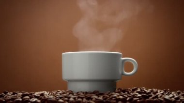 Beyaz fincan kahve çekirdekleri ile sıcak bir içecek buhar üzerinde