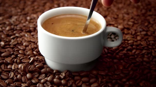 Side view of white cup of black coffe on coffee beans — Stock Video