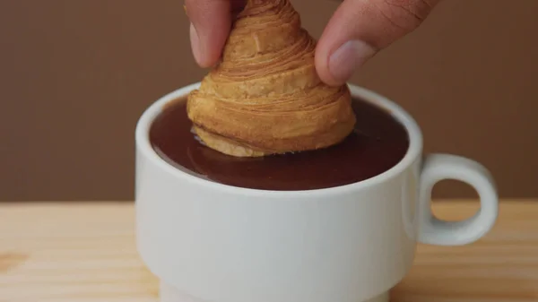 Closeup of croissant immerse into hot chocolate in cup — Stock Photo, Image