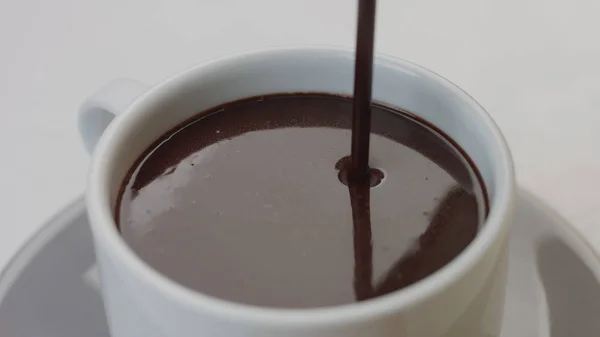 Bovenaanzicht van witte kop en warme chocolademelk gieten in het — Stockfoto