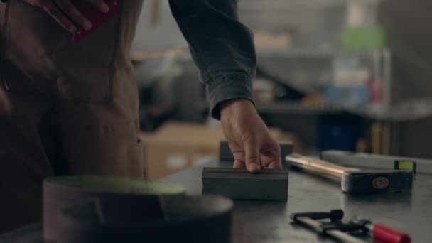 Работник в своем гараже готовит два металлических кирпича для сварки — стоковое видео