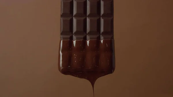 Nahaufnahme schwarzer Schokoriegel in flüssiger Schokolade getränkt — Stockfoto