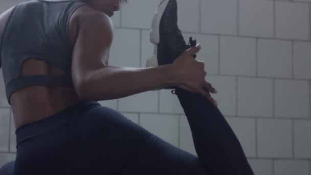 Close-up van gemengd ras african american vrouw maakt een stretching routin op de vloer in zonnige loft — Stockvideo