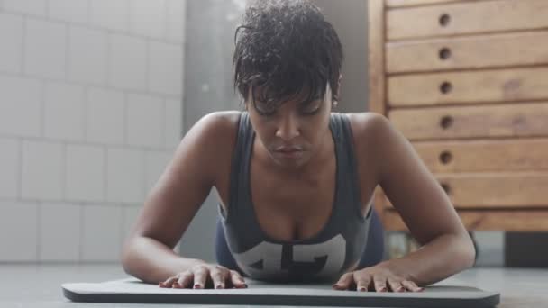 Jeune ajustement et tonifier femme faisant entraînement de remise en forme avec des éléments de planche pour abdos tendus dans loft ensoleillé — Video