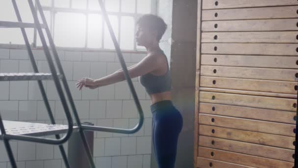 Jovem ajuste e tom para cima mulher fazendo aquecimento antes de um treino de fitness em loft ensolarado — Vídeo de Stock