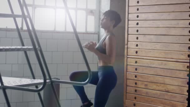 Junge fitte und straffere Frau beim Heizen vor einem Fitnesstraining im sonnigen Loft — Stockvideo