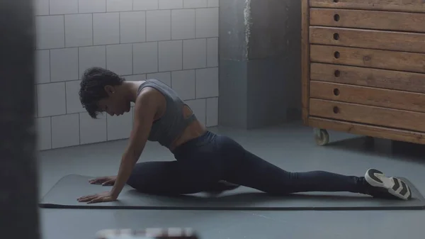 Närbild av blandad ras afroamerikanska kvinna gör en stretching rutin på golvet i sunny loft — Stockfoto
