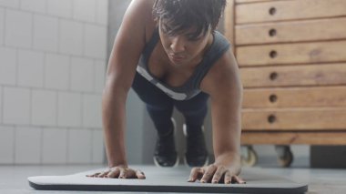 Genç zinde ve ses kadının yapması için güneşli çatı katında güç abs fitness egzersiz tahta elemanları ile yukarıya