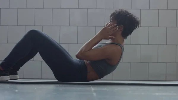 Sidovy av svart kvinna gör en abs routin på golvet jag synny loft — Stockfoto