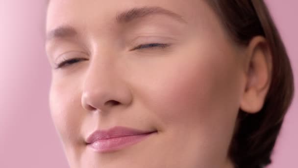 Крупный план женщины на розовом фоне улыбающейся — стоковое видео
