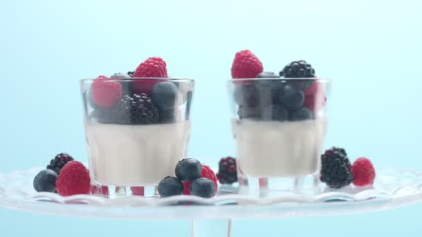 Прозорі окуляри, повні йогурту, пана-кота, білий ванільний мус, прикрашений ягодами — стокове відео