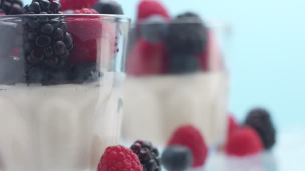 Transparent glasses full of yogurt, panna cotta, white vanilla mousse decorated with berries — Stock Video