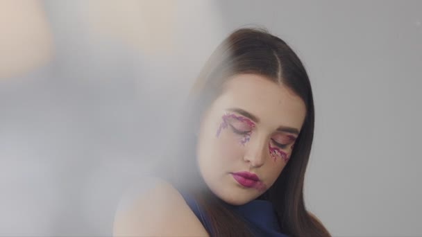 Mladý model s fashin make-up v purpurové tóny v studio pro natáčení — Stock video