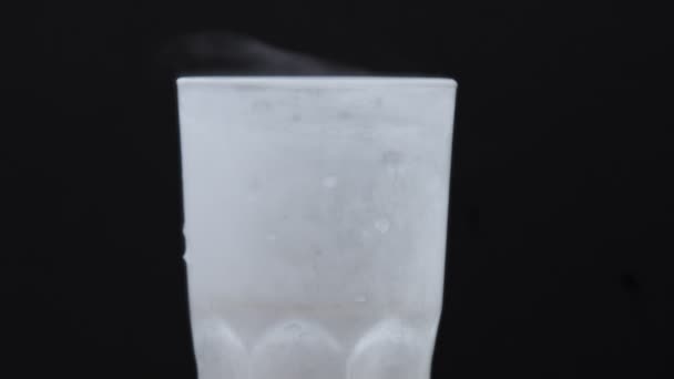 Стакан со льдом и ломтиком лимона на черном с домашним лимонадом, льющимся в него — стоковое видео