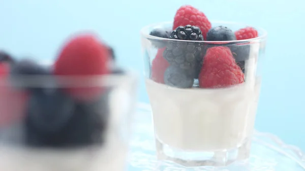 Transparent glasses full of yogurt, panna cotta, white vanilla mousse decorated with berries — Stock Photo, Image