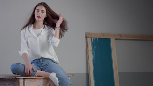 Mulher no estúdio industrial usa jeans e camisa branca — Vídeo de Stock