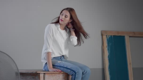 Жінка в промисловій студії носить джинси і білу сорочку — стокове відео