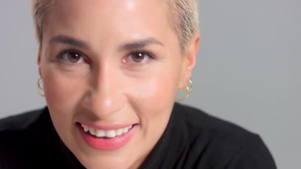 Blondynka z krótką fryzurą w studio pozuje do aparatu fotograficznego na szarej skórze — Wideo stockowe