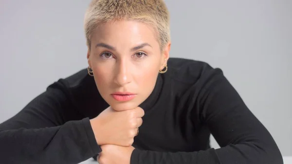 Blonde with short haircut in studio poses for camera on grey Ideal skin — Stock Photo, Image