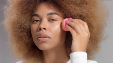 Stüdyoda uzun saçlı, melez bir zenci kadın krema lekesi koymuş.