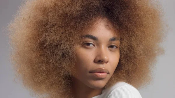 Mischling schwarze Frau mit großen Afro-Haaren im Studio legte einen cremefarbenen Fleck — Stockfoto