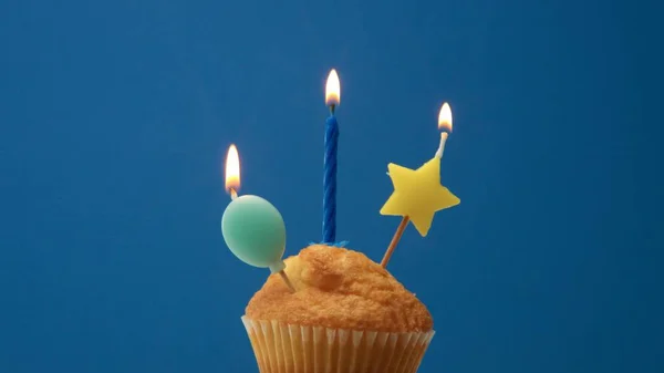 Muffin with some candle decoration on a blue background — Stock Photo, Image