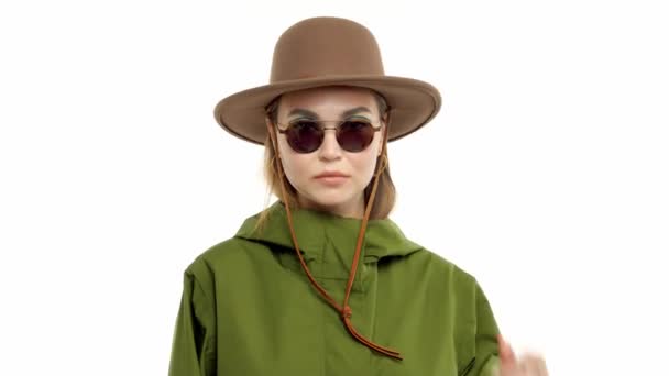 Woman in a autumn look in studio in green parka and hat turns and poses to the camera — 비디오