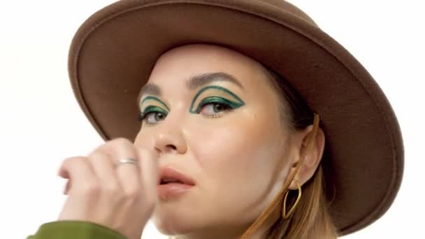 Woman in a autumn look in studio in green parka and hat turns and poses to the camera — Stock Video