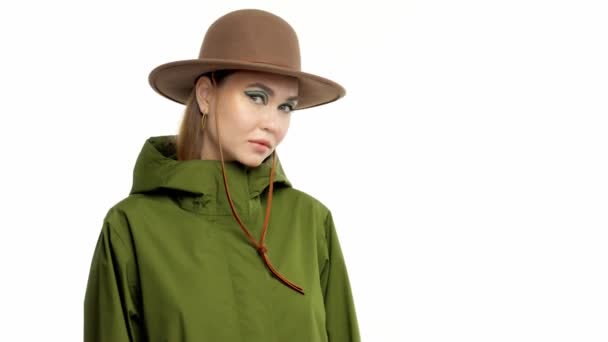 Donna in un look autunnale in studio in verde parka e cappello gira e posa alla macchina fotografica — Video Stock