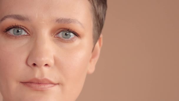 Kaukasische Frau mit Kurzhaarschnitt und natürlichem beige Make-up im Studio auf beigem Hintergrund — Stockvideo