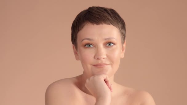 Caucasian woman with short haircut and natural beige makeup in studio on beige background — 图库视频影像