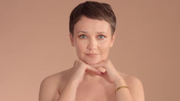 Caucasian woman with short haircut and natural beige makeup in studio on beige background — 图库视频影像