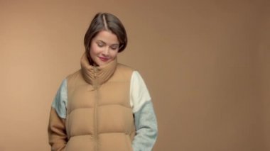 Caucasian brunette model in studio on beige background wear a sleeveless jacket