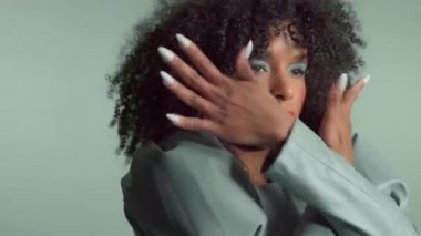 Stüdyoda deri elbiseli, kıvırcık saçlı, melez bir kadın.