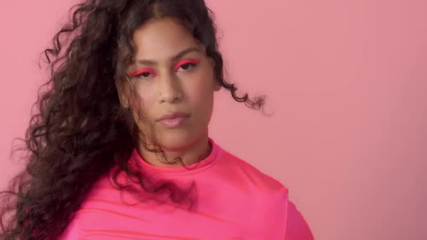 Ung kvinna i studio på rosa bär en neon polotröja och neon makeup — Stockvideo