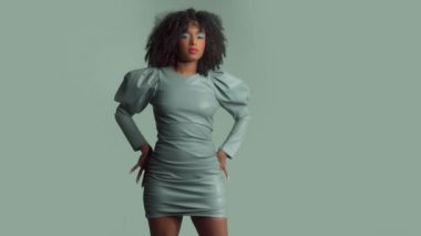 Stüdyoda deri elbiseli, kıvırcık saçlı, melez bir kadın.