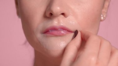 30 'lu yaşlardaki esmer kadın pembe arka planda stüdyo için ideal cilde sahip dekolte bir bluz giyiyor.