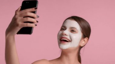 30 'lu yaşlardaki esmer kadın pembe arka planda stüdyo için ideal cilde sahip dekolte bir bluz giyiyor.