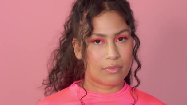 Ung kvinna i studio på rosa bär en neon polotröja och neon makeup — Stockvideo