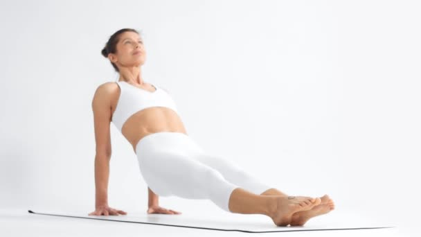 Mujer mayor en el espacio blanco practica yoga — Vídeo de stock