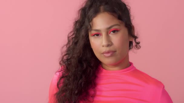 Ung kvinna i studio på rosa bär en neon polotröja och neon makeup — Stockvideo