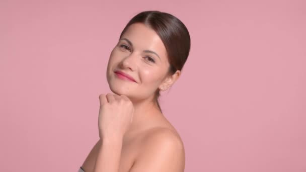 30s brunette woman wears a decollete top with ideal skin in studio on pink background — Stock Video