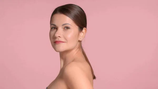 30s brunetka žena nosí dekolt top s ideální pleť ve studiu na růžovém pozadí — Stock fotografie