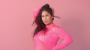 Pembe stüdyodaki genç kadın neon balıkçı yaka ve neon makyaj giyiyor.