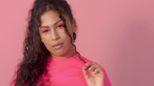 Mladá žena ve studiu na růžové nosí neonový rolák a neonový make-up — Stock video