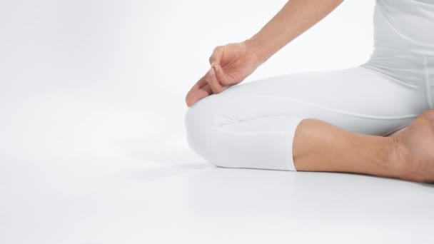 Unrecognizable woman in white space practice yoga sits in lotus position with hands on knees — 비디오